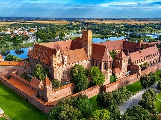 Aerial view of the sprawling Malbork Castle and surrounding landscape.
