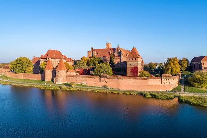 Scenic view of Malbork Castle across the river on a clear day.