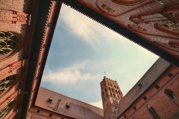 Courtyard view looking up at the sky framed by Malbork Castle's rooflines.