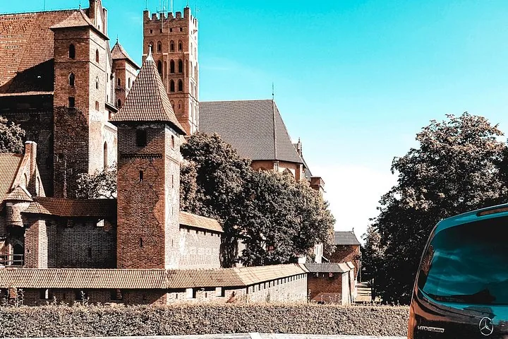 Exterior view of Malbork Castle walls and towers with a vehicle.