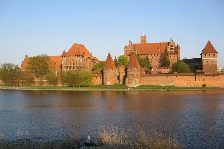 Wide view of Malbork Castle situated along the riverbank.