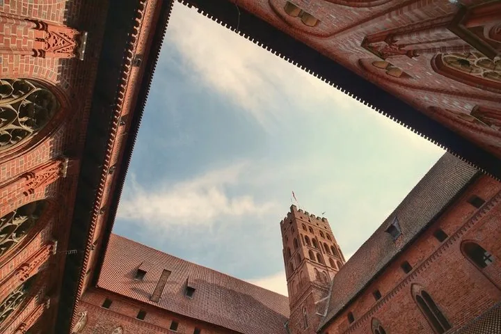 Looking up from a courtyard at the brick walls of Malbork Castle.