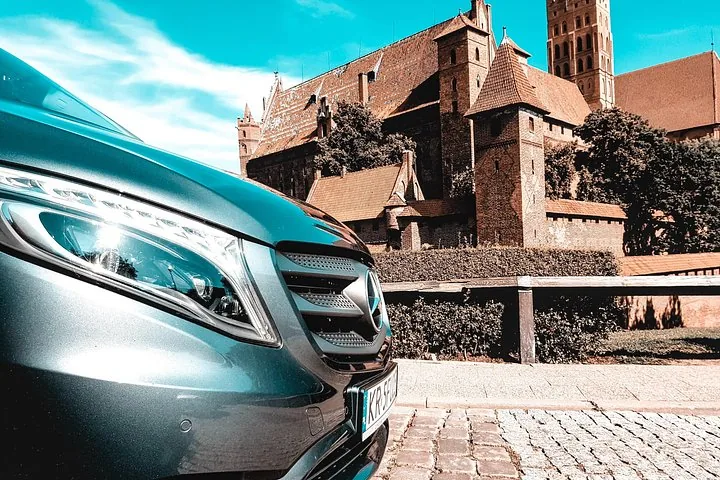 Close-up of a vehicle with Malbork Castle in the background.