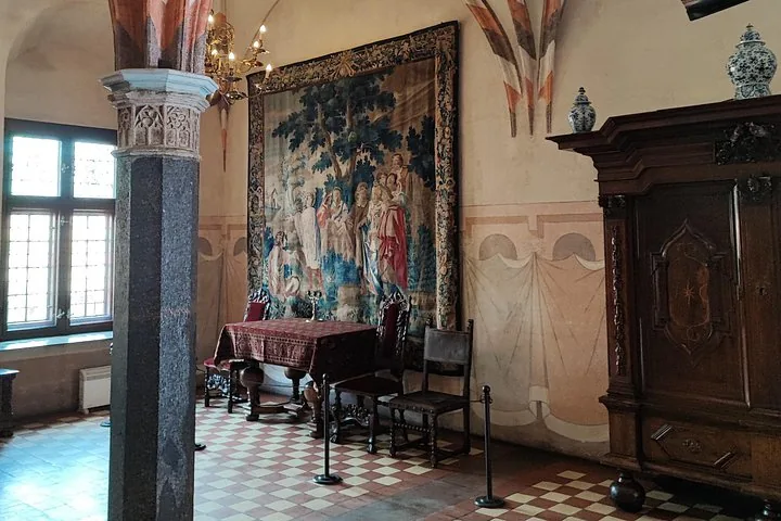 Interior room of Malbork Castle with tapestry, furniture, and tiled floor.